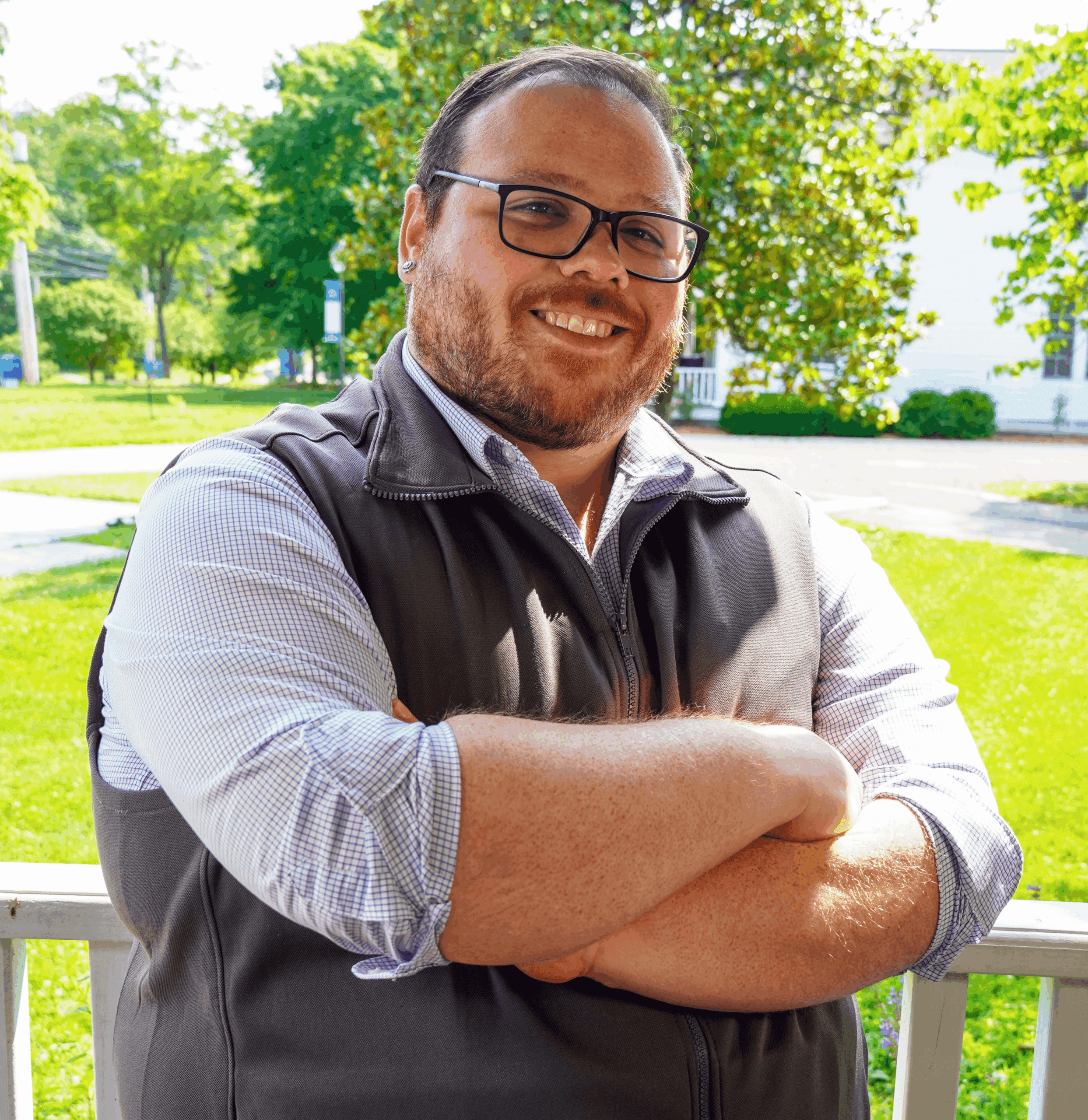 A photo of Regional Admissions Manager for the East Tennessee region, Christian Gentzel, standing outside with his arms crossed, leaning against a white railing, and smiling.
